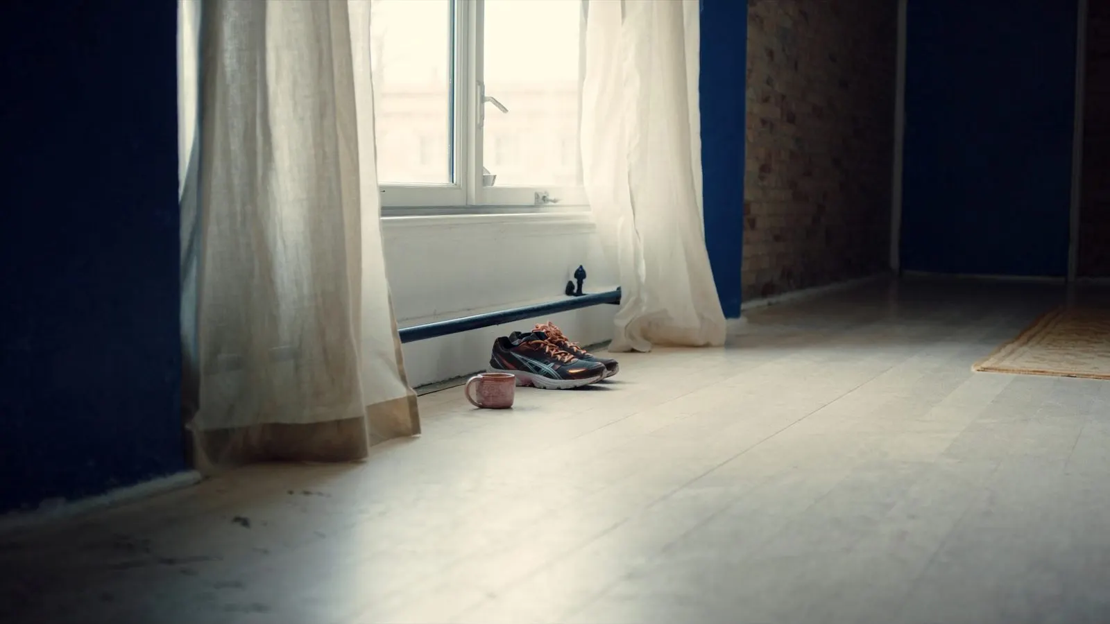 Editorial photograph of premium running shoes beside a large window with soft morning light, a ceramic mug of coffee nearby.