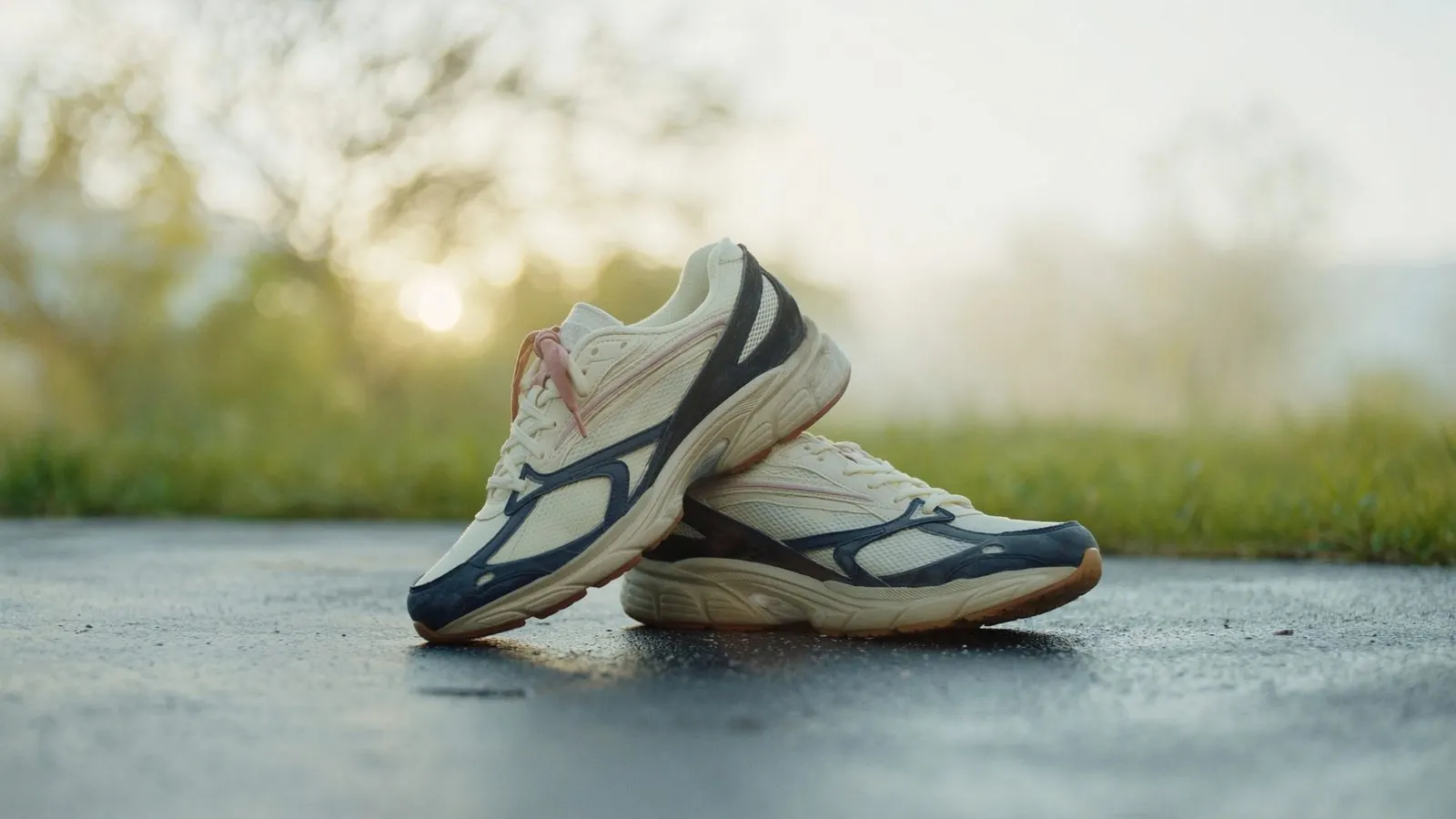 Editorial close-up of running shoes on dawn pavement, soft warm light, cream and navy palette.