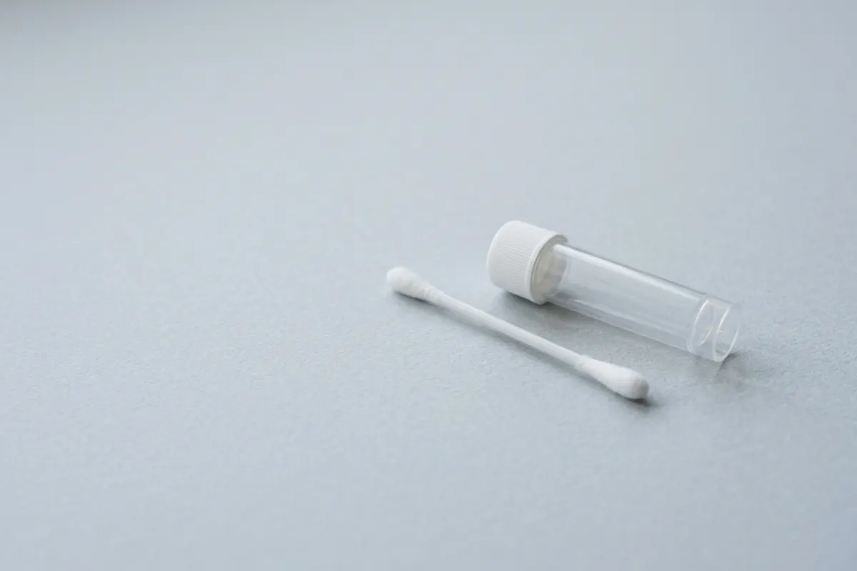 An unlabeled saliva sample tube and a swab
