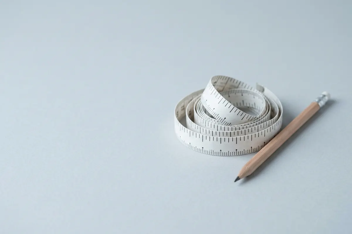 A coiled tape measure and a pencil