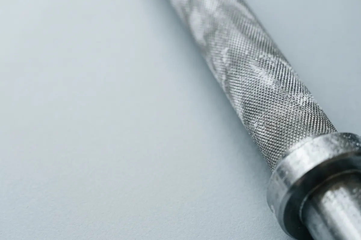The knurled sleeve of a barbell dusted with chalk
