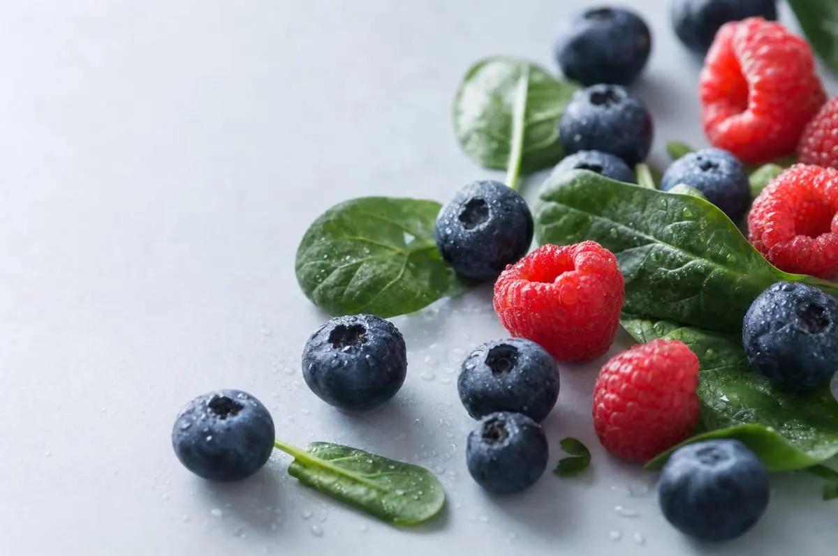 Fresh blueberries, raspberries and spinach with water droplets