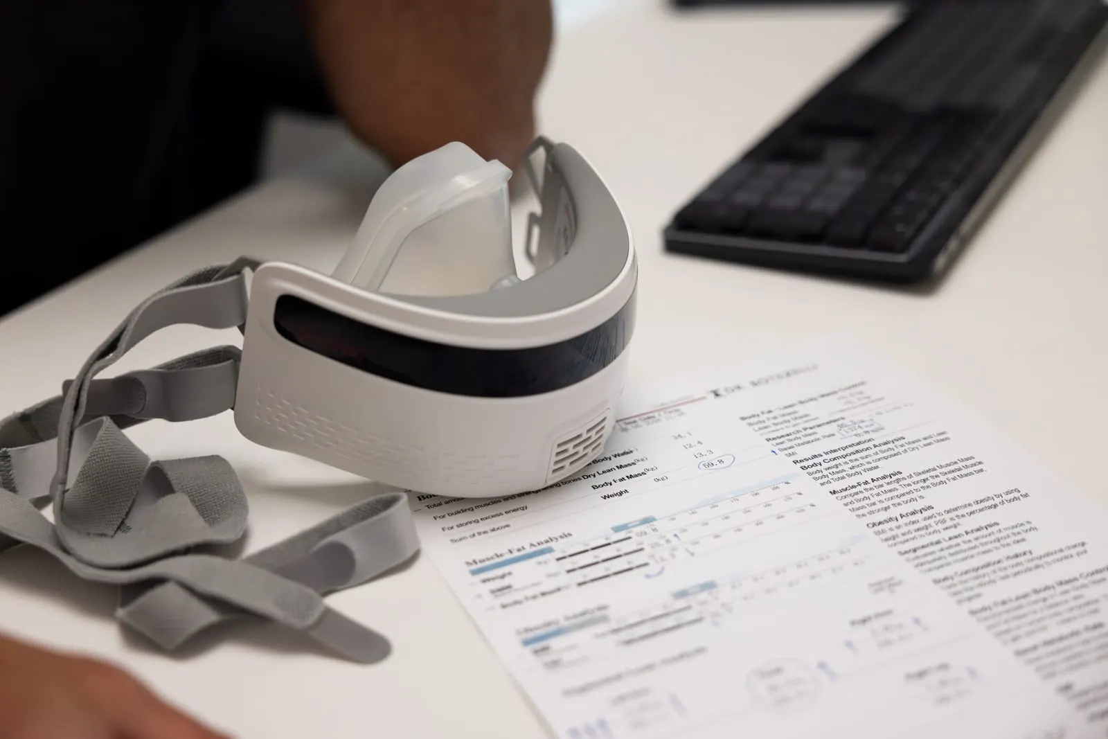 The Breezing indirect-calorimetry mask on the studio desk beside a printed body-composition report