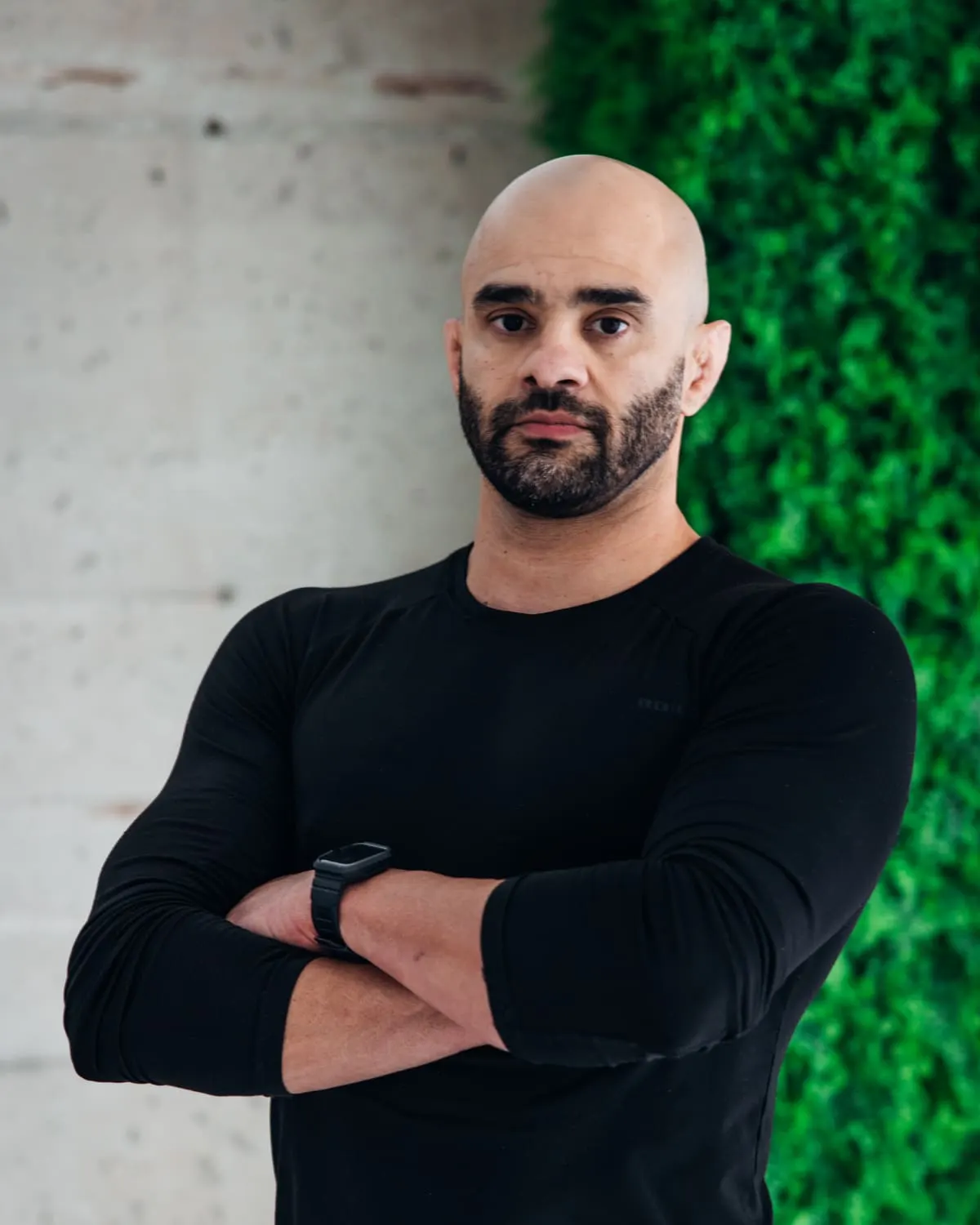 JD Botezelli PhD with his arms crossed, in a black long-sleeve shirt